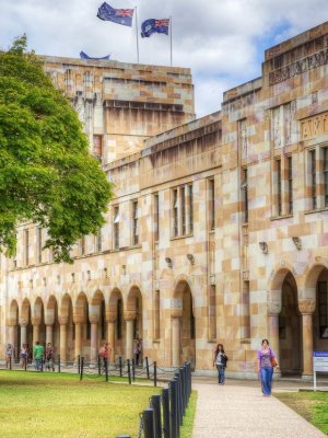 The sandstone buildings of UQ's Great Court with people wandering in the background.